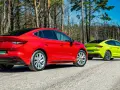 Dwa samochody Skoda Enyaq w kolorach czerwonym i limonkowym na leśnej drodze.