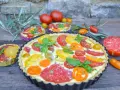 Eine herzhafte Tomaten Quiche mit bunten Tomatenscheiben und frischem Basilikum, garniert mit Lavendelblüten.