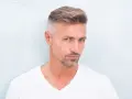 Hombre con barba corta y cabello peinado, luciendo un estilo moderno. Decidió dejarse perilla para un look más definido.