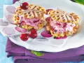 Zwei herzförmige Waffeln gefüllt mit Kirscheis und Schokostückchen, garniert mit frischen Kirschen. Ein süßer Genuss!