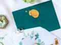 Elegancka koperta z pieczęcią, obrączki i zaproszenie. Zastanawiasz się, ile trzeba dać w kopercie na wesele?