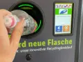 Ręka wrzuca butelkę do automatu. Niemiecki system kaucyjny działa sprawnie, zwracając 0,25 EUR za każdy zwrot.