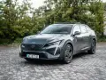 Nowy Peugeot 408 w ciemnoszarym kolorze prezentuje się elegancko na tle zieleni.