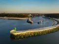 Port w Mrzeżynie z falochronami i latarniami morskimi. Widoczna łódź pogłębiarka. Mrzeżyno atrakcje dla miłośników morza.