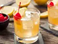 En gyllene whiskey sour med is, citron och körsbär. En klassisk drink som passar perfekt en varm dag.