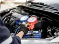 Mechanic checks car AC pressure with gauges. This helps determine how much to fix AC in car.