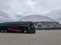 Czarny autokar firmy Eurotrans przed nowoczesnym budynkiem z kopułą.