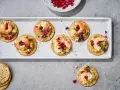 Mediterranes Fingerfood kalt: Garnelen auf Avocado-Creme mit Granatapfelkernen und Kräutern auf Crackern.