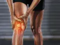 Person hält schmerzendes, dickes Knie. Was tun bei Knieproblemen? Rote Hitze zeigt Entzündung.