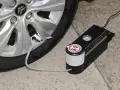 Riparazione di una gomma bucata con kit di gonfiaggio. Il compressore è collegato alla valvola del pneumatico.