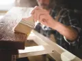 Carpintero aplicando barniz a madera, mostrando la diferencia entre laca y barniz.