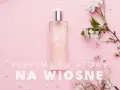 Elegancka butelka perfum otoczona delikatnymi, białymi kwiatami. Idealne perfumy kwiatowe na wiosnę.
