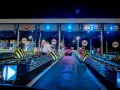 Nocny widok na bramki autostradowe z niebieskimi światłami i znakami, samochody wjeżdżają na płatne pasy.