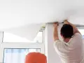 Montaż białego sufitu napinanego. Wady mogą pojawić się przy niedokładnym naciągnięciu materiału.
