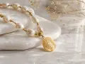 Elegancki łańcuszek z pereł i złotą monetą, idealny na prezent. Wiele przesądów wiąże się z noszeniem pereł i amuletów.