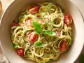 Zucchini-Spaghetti mit cremiger Sauce, Kirschtomaten und Basilikum. Ein leichtes Gericht, das sich perfekt zum Kochen oder Braten eignet.
