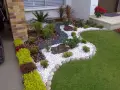 Piccoli giardini da sogno con ghiaia bianca, pietre scure, piante verdi e fiori rossi, un'oasi di pace.