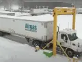 Ciężarówka z naczepą Airgas pod żółtą bramownicą w śnieżny dzień.