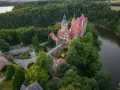 Zamek Czocha, malowniczo położony na skalistym cyplu nad rzeką, otoczony bujną zielenią.