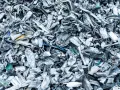 Góra poskręcanego, poszarpanego złomu metalowego, gotowego do recyklingu metalu. Widać fragmenty niebieskiego i żółtego plastiku.