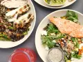 Två skålar med mat: en med grillad kyckling och vildris, en annan med lax och sallad. Perfekt för att få i sig rätt mängd protein per kilo kroppsvikt.