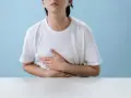Persona con le mani sull'addome, che esprime disagio per nausea e giramenti di testa dopo allenamento.
