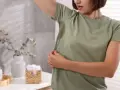 Kobieta z mokrą od potu pachą, czując nieprzyjemny zapach octu w pocie.
