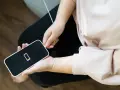 En person kopplar in sin iPhone som drar mycket batteri. Batteriikonen visar låg laddning.