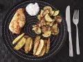 Ein Teller mit Hähnchenbrust, Kartoffelspalten und Zucchinigemüse, perfekt für Airfryer Rezepte. Dazu ein Klecks Dip.