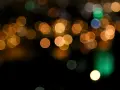 Des lumières de ville floues créent un arrière-plan bokeh chaleureux, avec des cercles dorés, verts et bleus sur fond noir.