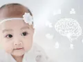 Urocze dziecko z białą opaską na głowie, obok świecący mózg symbolizujący rozwój mózgu dziecka i ikony związane z niemowlęciem.
