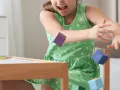 Ein Mädchen in einem grünen Kleid wirft bunte Holzklötze. Ein Versuch, laute Kinder zur Ruhe zu bringen, indem man sie zum Spielen anregt.