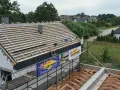 Budowa dachu z blachą i membraną. Pracownik na rusztowaniu montuje pokrycie.
