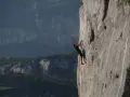 Wspinacz pokonuje pionową ścianę skalną w Arco. W tle góry i dolina.