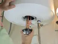 Un tecnico ripara uno scaldabagno che attacca e stacca, mostrando le resistenze in rame.