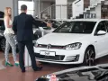 Sprzedawca prezentuje biały samochód flotowy Volkswagen Golf klientce w salonie samochodowym.