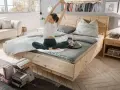 Frau dehnt sich im hellen Schlafzimmer. Ein gemütliches Bett, ein Sofa und Bücher laden zum Entspannen ein. Perfekt, um das Schlafzimmer einzurichten.