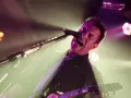 Chanteur criant dans un micro, guitare en main. L'éclairage d'ambiance crée une atmosphère intense pour ce reglage photo concert.