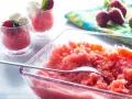 Erfrischende Erdbeer Granita in einer Glasschale, garniert mit frischen Erdbeeren und Sahne in kleinen Gläsern.