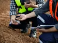 Pracownicy w kamizelkach odblaskowych analizują próbki ziemi, wykonując badania geotechniczne gruntu.