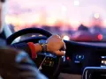Uomo al volante, con un orologio al polso, pronto per un nuovo uber lavoro al tramonto.