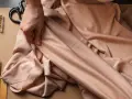 Mains tenant un tissu drapé, avec des épingles, des ciseaux et du fil. La viscose, c'est quoi ? Une matière douce et fluide pour la couture.