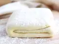 Gotowe ciasto francuskie, idealne do nauki, jak zrobić ciasto francuskie. Warstwy ciasta posypane mąką.