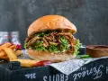Saftiger pulled pork burger mit Salat, Jalapeños und Gurken. Die Zutaten für diesen Burger sind perfekt aufeinander abgestimmt. Dazu Pommes und Dip.