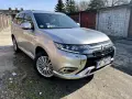 Srebrny Mitsubishi Outlander PHEV na tle garaży. Wiele osób szuka mitsubishi outlander opinie przed zakupem.