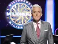 Hubert Urbański w garniturze, na tle koła z napisem "Milionerzy". Co dajemy komuś na drogę milionerzy? Wiedzę i odwagę!