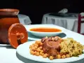 Plato de cocido madrileño con garbanzos, carne, repollo y sopa en un cuenco.