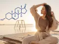 Kobieta w medytacyjnej pozie na plaży, obok wzór chemiczny DHEA-S. Podwyższony poziom tego hormonu może wymagać leczenia.