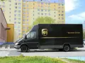 Czarny van UPS z napisem "Worldwide Services" na tle bloku mieszkalnego. Zastanawiasz się, ile zarabia kurier UPS?