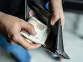 Ręce wkładają polskie banknoty 200 zł do portfela. Czy można mieć dwóch komorników na pensji, gdy pieniędzy jest tak mało?